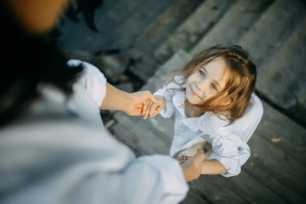 Putri dan ibu berpegangan tangan dan anak itu menatap ibunya Stok Foto Bebas Royalti