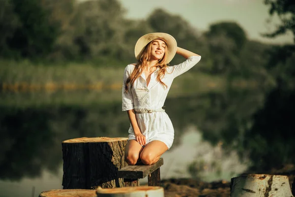 Mujer joven y bonita está sentada en el banco junto al río . —  Fotos de Stock