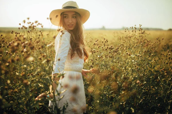 漂亮的年轻女子走在草地上的花丛中. — 图库照片