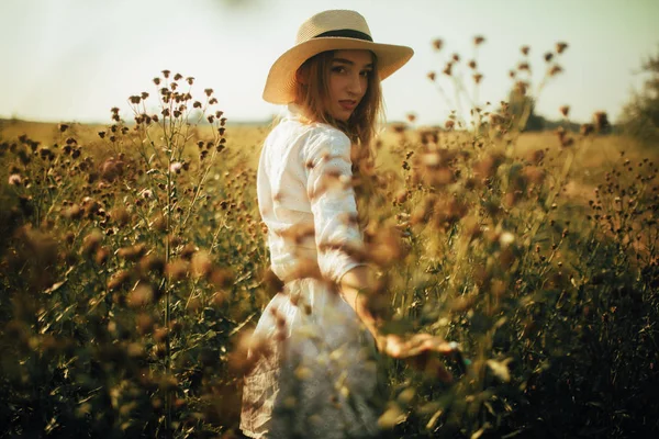 Hübsche junge Frau spaziert zwischen den Blumen auf der Wiese. — Stockfoto