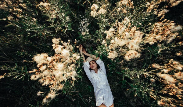 Mujer joven y bonita yace entre las flores y la hierba en el meado —  Fotos de Stock