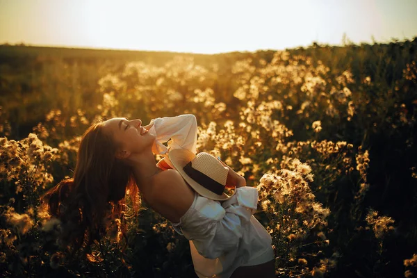 Mutlu genç kadın mead üzerinde çiçek ve çim arasında yürüyor