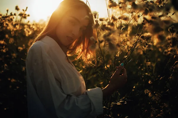 Glückliche junge Frau spaziert zwischen Blumen und Gras auf der Wiese — Stockfoto