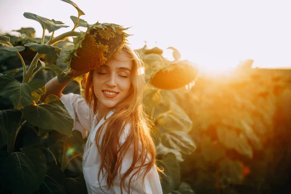 Porträt einer glücklichen Frau neben Sonnenblumen bei Sonnenuntergang. — Stockfoto