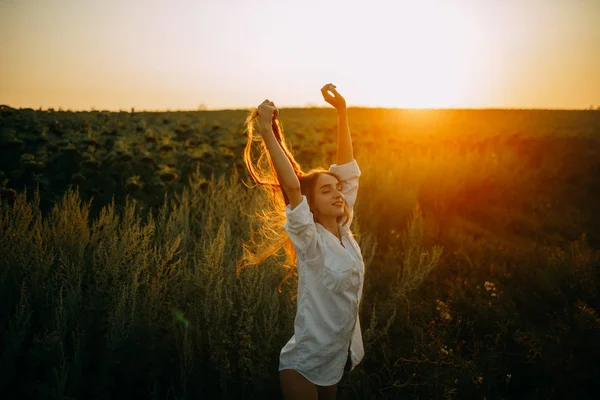 Fröhliche Frau spaziert bei Sonnenuntergang auf Wiese. — Stockfoto