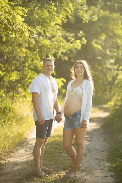 Pár terhes nő tartja kezében az erdei ösvényen. — Stock Fotó