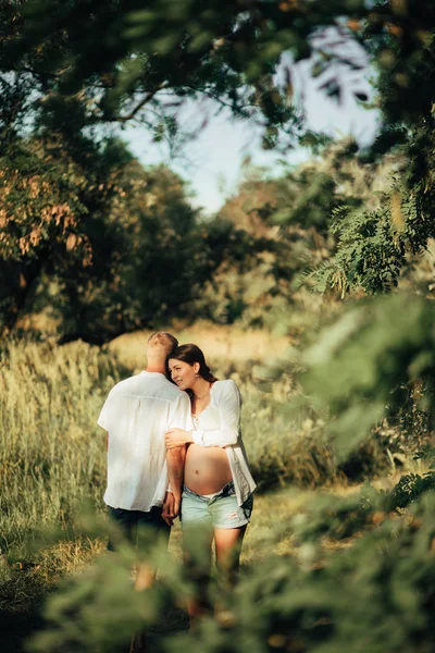 Pareja con mujer embarazada abraza en el bosque . —  Fotos de Stock