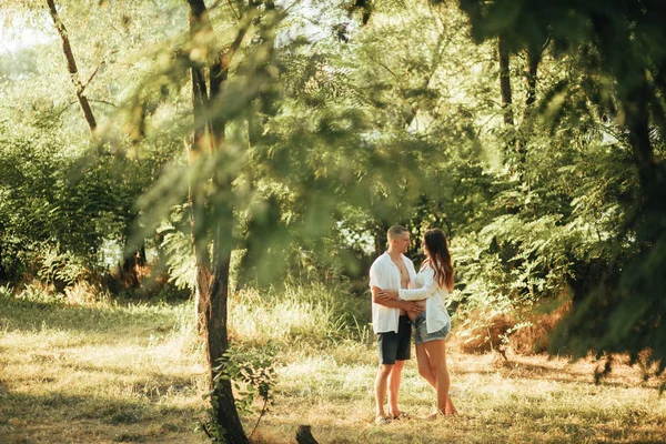 Hamile kadın ile çift ormanda kucaklıyor. — Stok fotoğraf