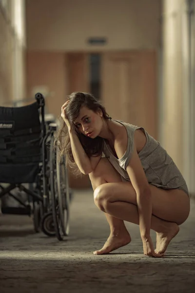A beaten woman victim of violence sits in a hospital corridor. — Stock Photo, Image
