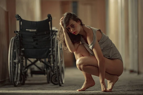 A beaten woman victim of violence sits in a hospital corridor. — Stock Photo, Image