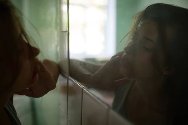 Femeia bătută cu sânge victimă a violenței își examinează rănile faciale în oglindă . — Fotografie, imagine de stoc