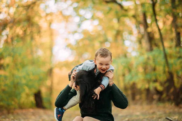 Мати і син грають, розважаються і сміються в осінньому лісі . — стокове фото