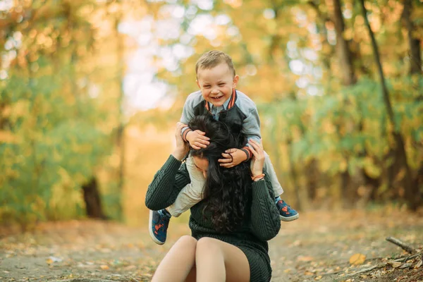 妈妈和儿子在秋天的森林里玩耍，玩得开心，笑得开心. — 图库照片