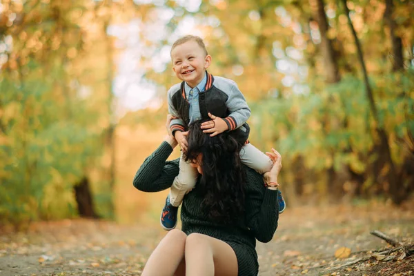 Una madre y un hijo juegan, se divierten y se ríen en el bosque de otoño . —  Fotos de Stock
