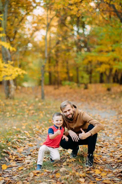 Un padre y un hijo se sientan en un sendero en el bosque de otoño . —  Fotos de Stock