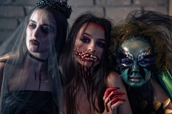 Three women in a carnival costumes of a vampire bride, bloody mutant and witch. — Stock Photo, Image