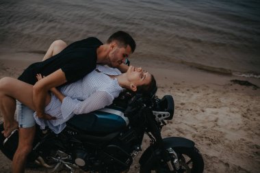 Çiftler plajda sevişiyor. Motorsikletin üstünde su üstünde yatıyorlar..