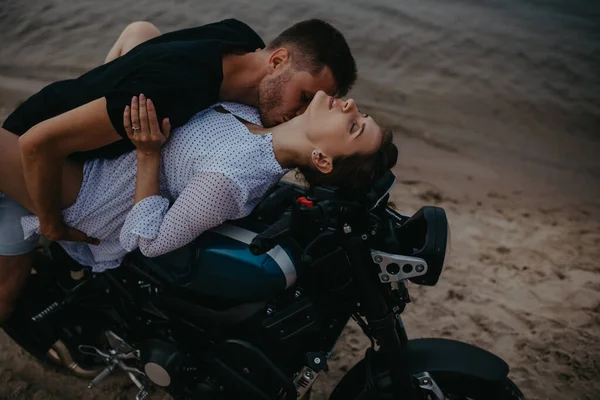 Couple makes love on beach lying on motorcycle on water background. Closeup.