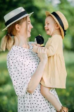 Anne ve kızı şapkalarla parkta yürürken eğleniyorlar..