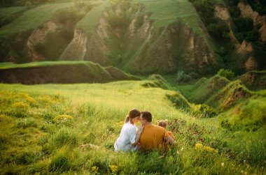 Küçük kızı olan aile vadi arka planında çayırda yürürken dinleniyor. Arka plan.