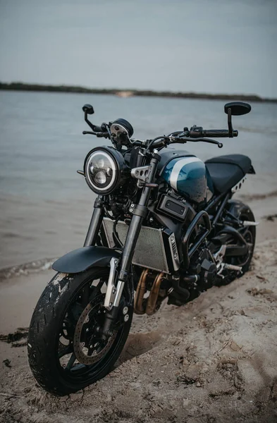 オートバイは空を背景に水の近くの砂浜にあります — ストック写真