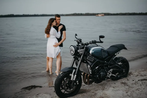 Pár Zamilovaných Stánků Objetí Okraji Vody Písečné Pláži Blízkosti Motocyklu — Stock fotografie