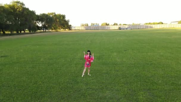 赤い着物の日本のバレリーナがジャンプし 芝生の上で体操の双子を実行します — ストック動画