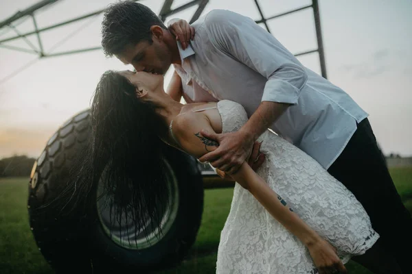 坠入爱河的夫妻在日落时分亲吻并拥抱在农用喷雾器的水滴中 — 图库照片