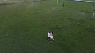 Birbirine aşık çiftler gün batımında tarımsal püskürtücüden su altında yürürler. İHA ateşi.