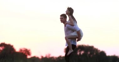 Birbirine aşık çiftler gün batımında çayırda eğlenip eğlenirler..