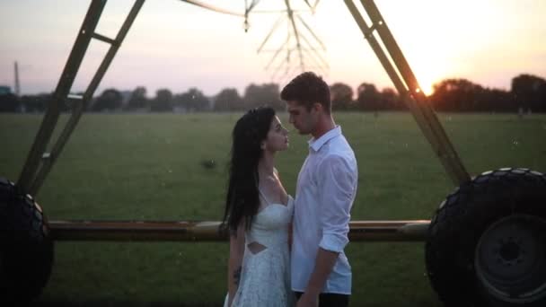 Szerelmesek Ölelkeznek Csókolóznak Vízcsepp Alatt Mezőgazdasági Permetezőből Naplementekor — Stock videók