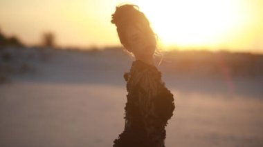 Dantelli siyah elbiseli kadın, gün batımında kumlu manzaranın arka planında çölde poz veriyor..