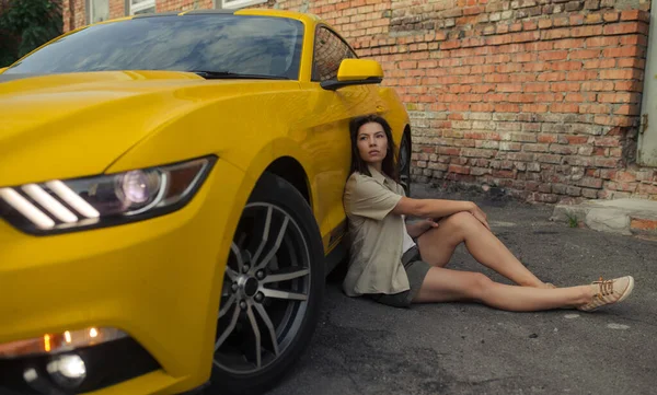 Jovem Mulher Senta Perto Carro Esporte Amarelo Contra Fundo Construção — Fotografia de Stock