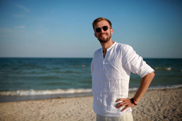 Joven Hombre Sonriente Gafas Sol Encuentra Playa Contra Mar Fondo — Foto de Stock