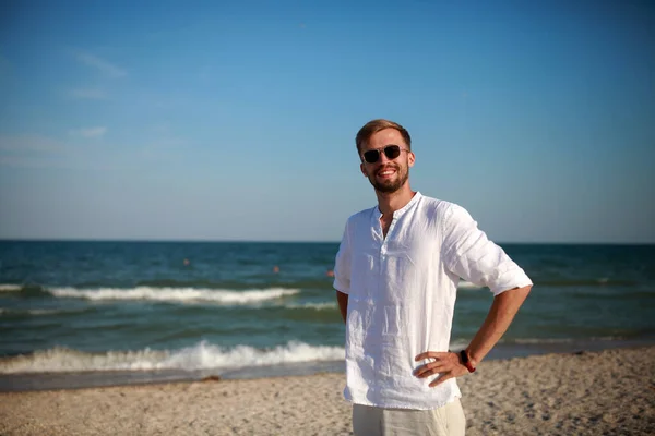 Joven Hombre Sonriente Gafas Sol Encuentra Playa Contra Mar Fondo — Foto de Stock