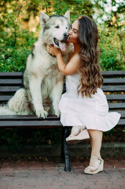 Doğuştan hastalıklı genç bir kadın cücelik yapıyor. Malamute köpeğinin yanında oturuyor, parkta yürürken sarılıp öpüyor..