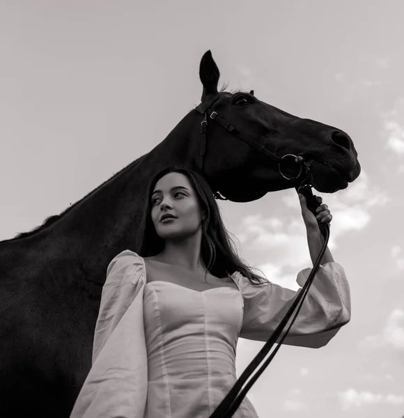 Νεαρή Γυναίκα Στέκεται Και Κρατά Άλογο Από Χαλινάρι Φόντο Ουρανού — Φωτογραφία Αρχείου