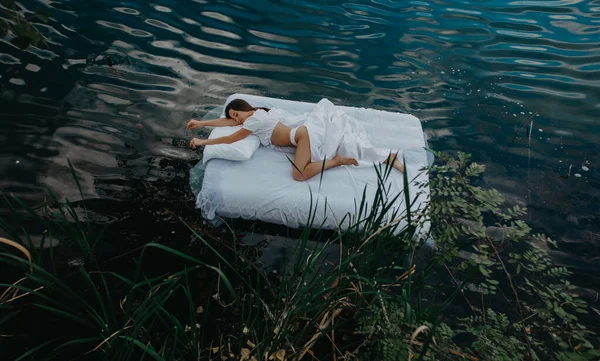 Młoda Kobieta Śpi Materacu Pływającym Wodzie Białą Pościelą Wśród Roślin — Zdjęcie stockowe