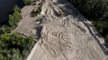 Kazı makineleri ve kumda lastik izleri olan bir kum ocağının drone görüntüsü. Kum madenciliği endüstrisi.