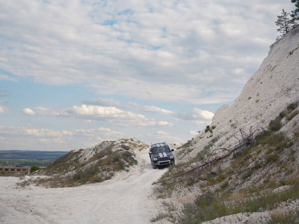 Военный пикап движется по грунтовой дороге, которая проходит через меловые холмы на востоке Украины. Атмосфера военных действий, война на Украине.