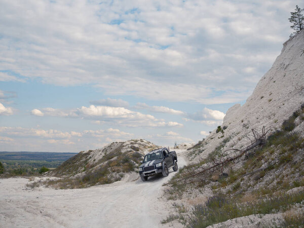 Военный пикап движется по грунтовой дороге, которая проходит через меловые холмы на востоке Украины. Атмосфера военных действий, война на Украине.