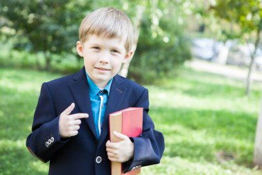 Bir çocuk elinde bir kitapla. Çocuk açık havada bir kitap okuyor. Çocuk bir kitap tutuyor.