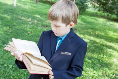 Bir çocuk elinde bir kitapla. Çocuk açık havada bir kitap okuyor. Çocuk bir kitap tutuyor.