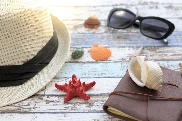 Summer concept with hat, sunglasses, diary, and seashells