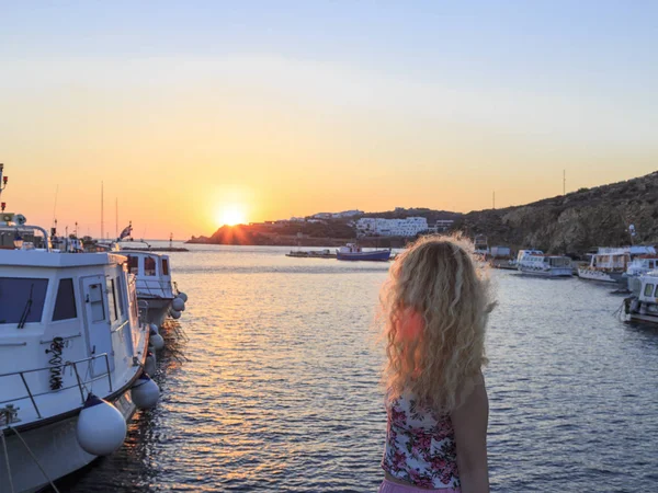 Blonde watching sunset in the new port of Mykonos in Mykonos, Greece