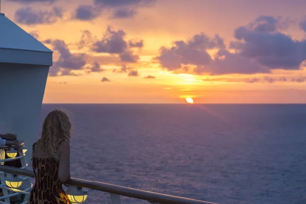 Blond watching sunset from cruise ship in caribbean sea near Philipsburg, St Martin