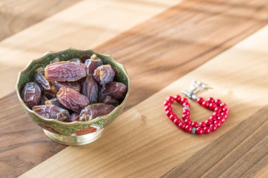 Metal plaka üzerindeki tarihlerle kahverengi masada kırmızı tespih