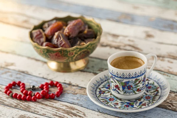 Turkish coffee, dates, and red rosary on turquoise table side view