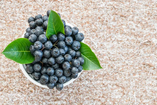Chokeberry 或黑楸楸在纺织背景的锅中 健康水果 图库图片