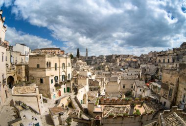 Matera antik şehir kaya içine oyulmuş. Şehrin eski taş bloklar. 2019-kültürel Avrupa'nın başkenti. Materinskii gorges town yakınındaki. Güzel manzara. İtalya. Beyaz bulutlar ile mavi gökyüzü karşı kentsel peyzaj